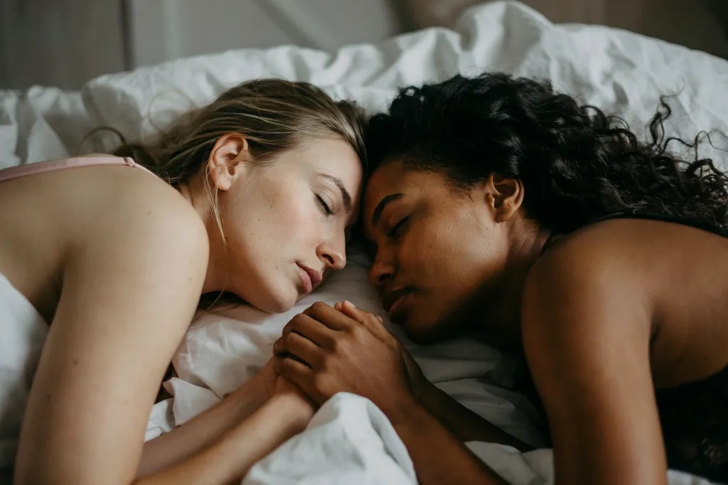 Two people in lingerie and underwear close together in warm light