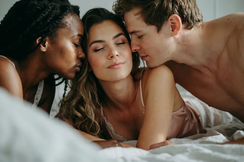 Three people in underwear together on white sheets